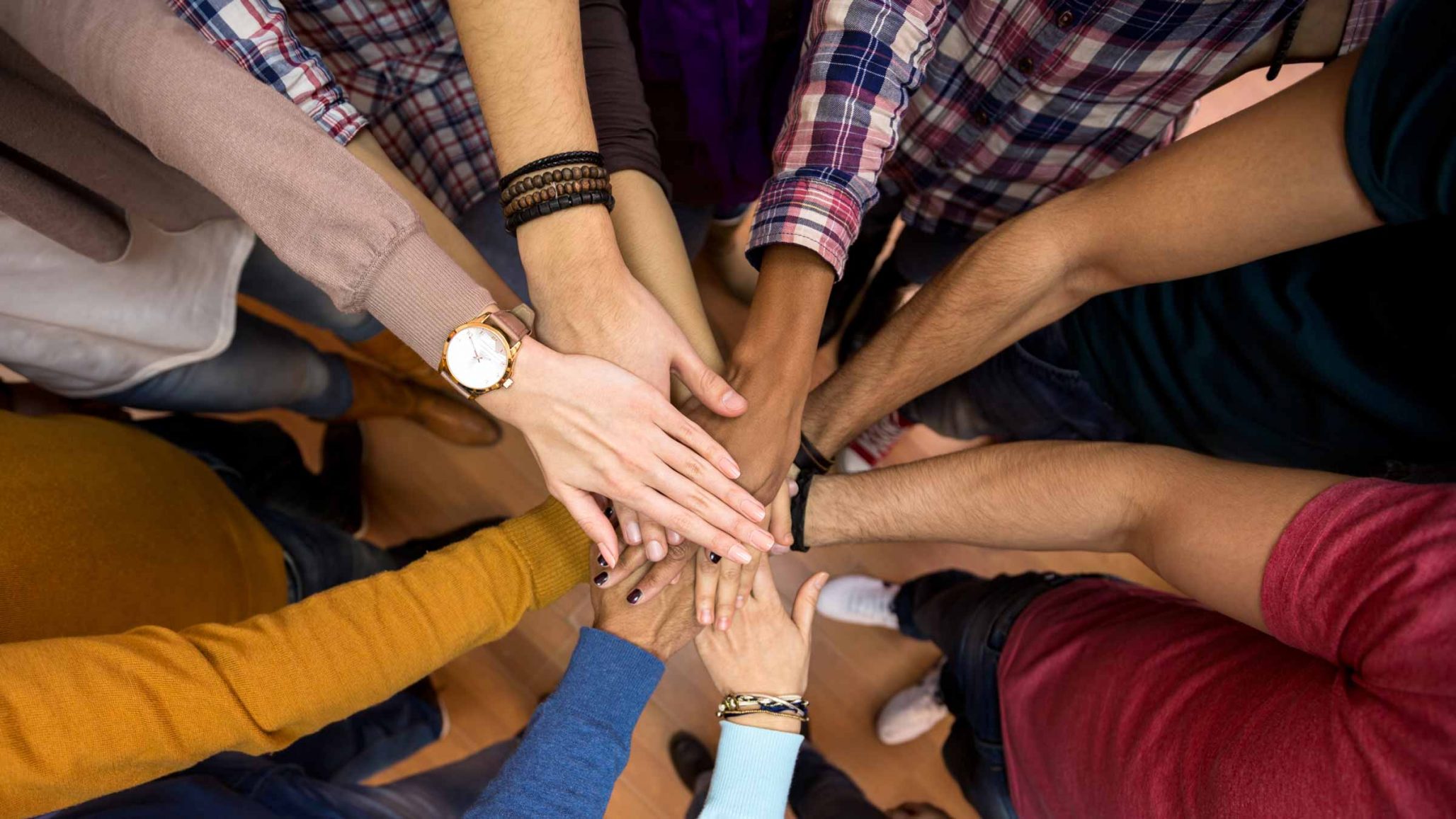 Hands of Teens and Adults reaching for the center of the image