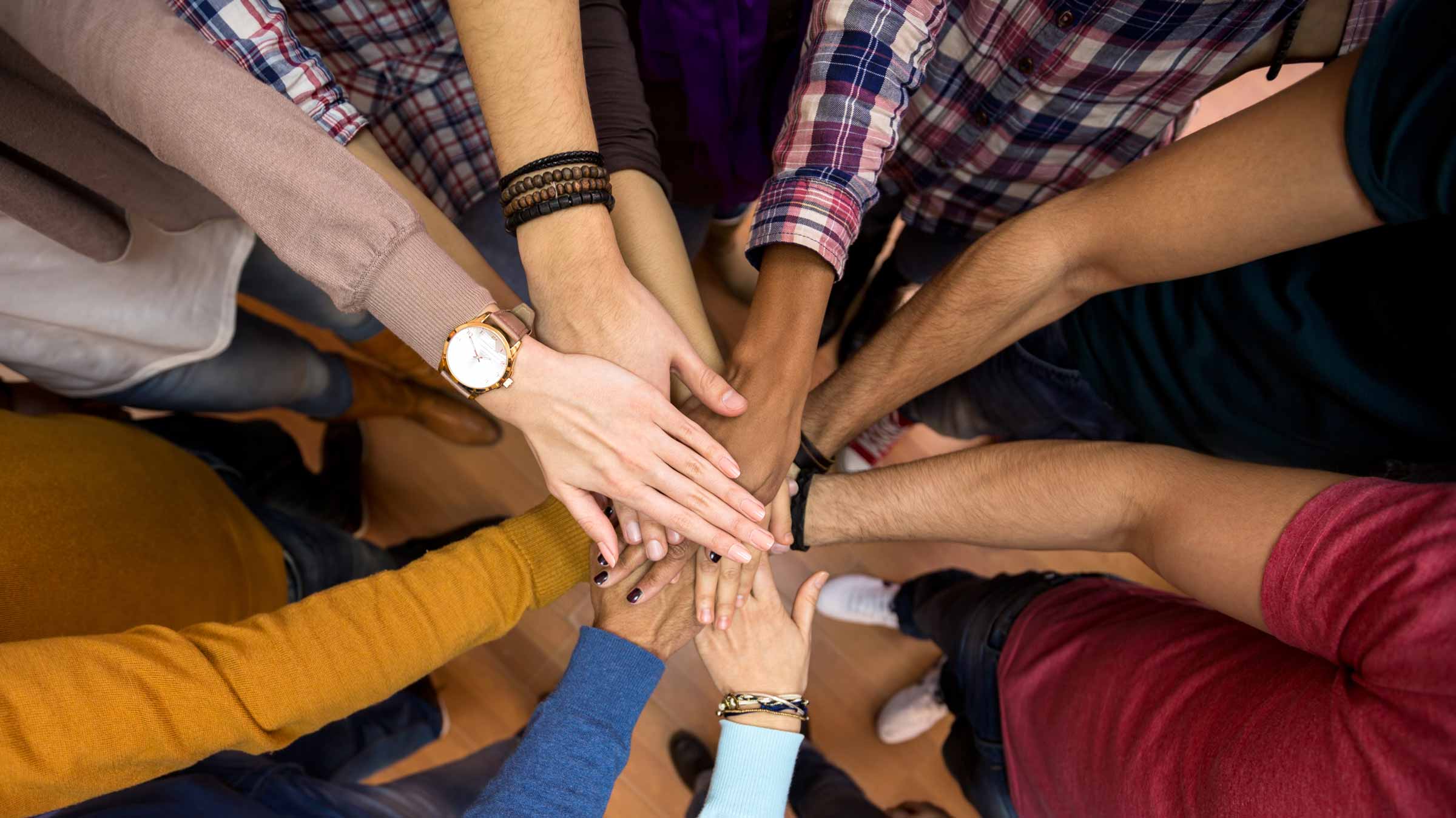 Hands of Teens and Adults reaching for the center of the image