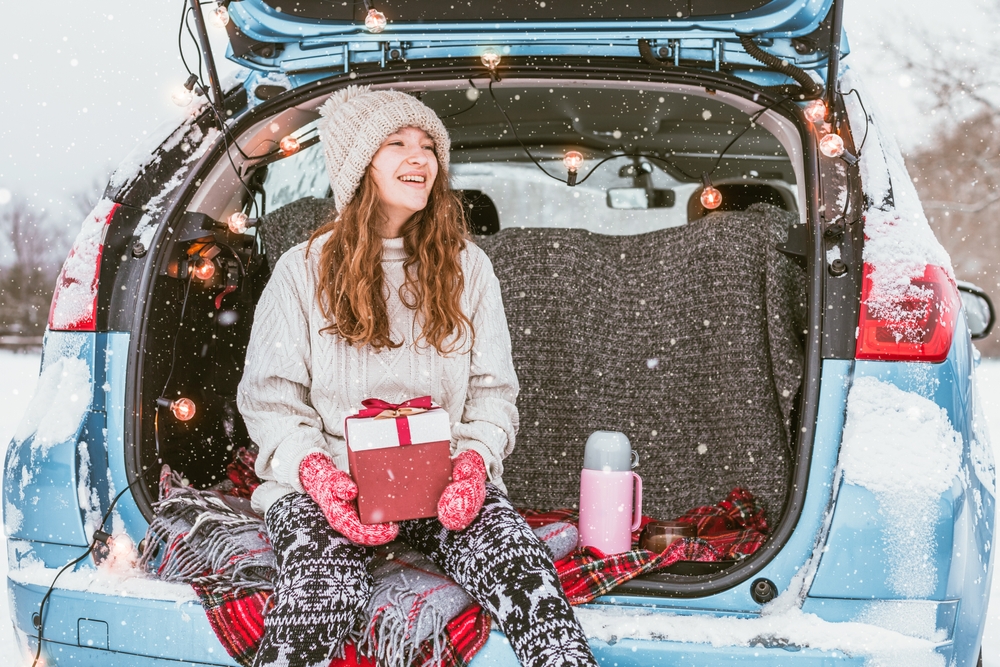 YoungWomanWithGiftSittingInCarTrunkInSnowy - ASAP Cincinnati